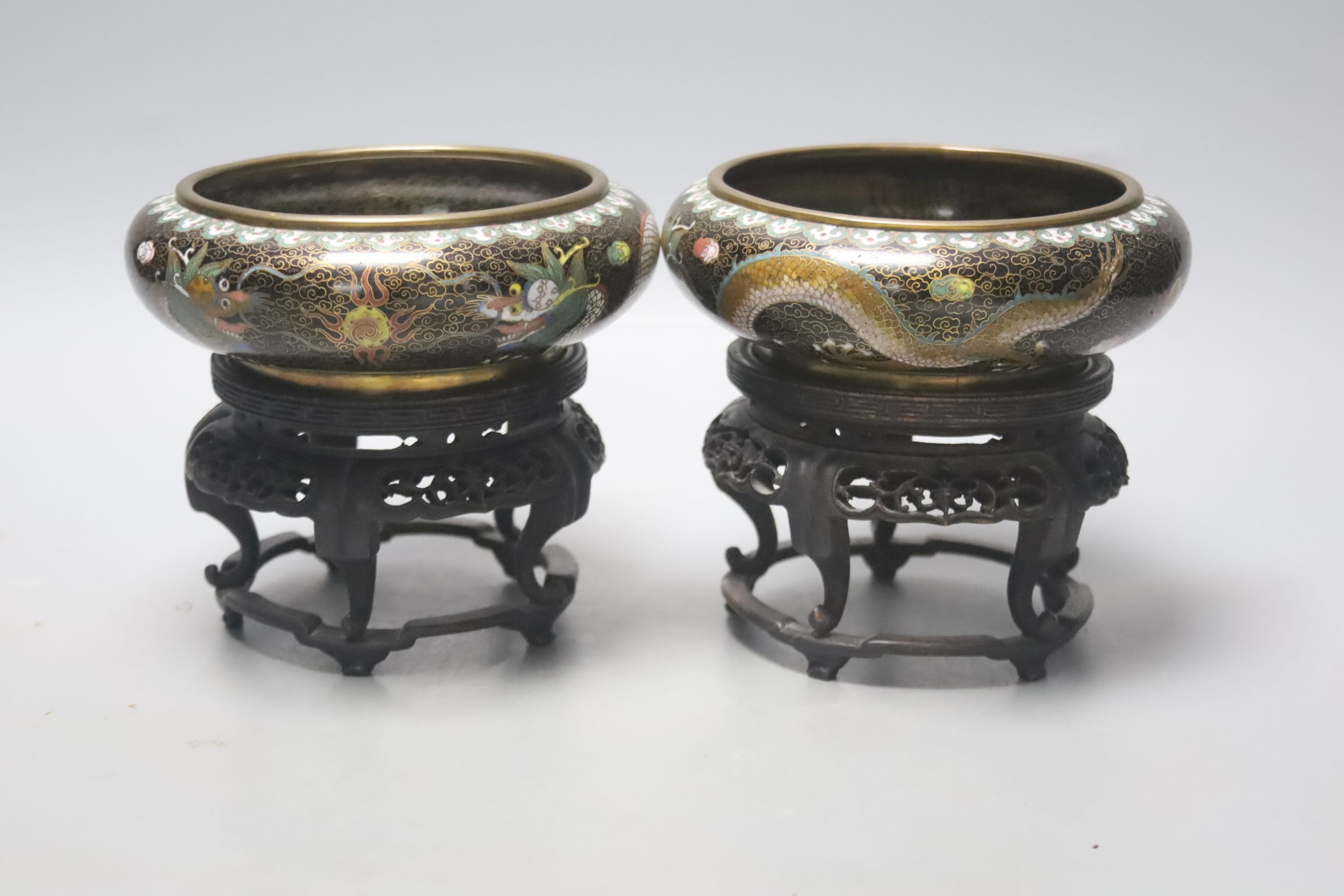A pair of Chinese cloisonne enamel small 'dragon' bowls, wood stands